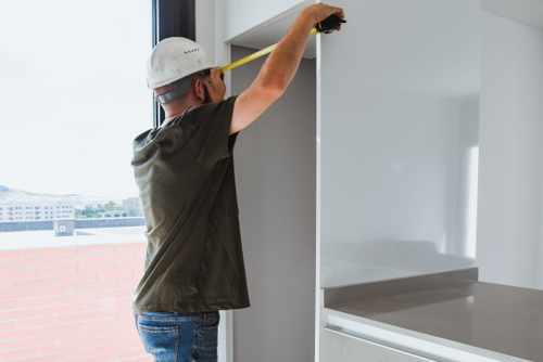 Contractor measuring cabinet cutout dimensions for built in refrigerator